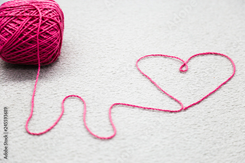 Pink heart of Pink wool yarn on a gray background