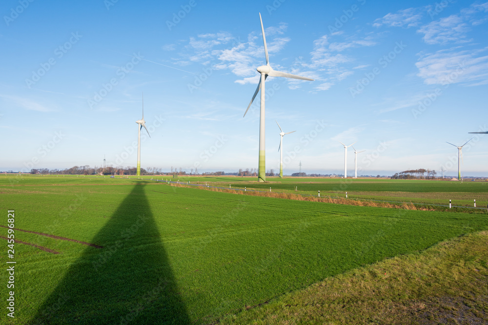 Windkraftanlagen zur ökologischen Stromversorgung sind in der windreichen ostfriesischen Küstenregion ideal zu betreiben. Im Hintergrund das Wattenmeer der Nordseeküste Windkraftanlagen zur ökologischen Stromversorgung sind in der windreichen ostfriesischen Küstenregion ideal zu betreiben. Im Hintergrund das Wattenmeer der Nordseeküste