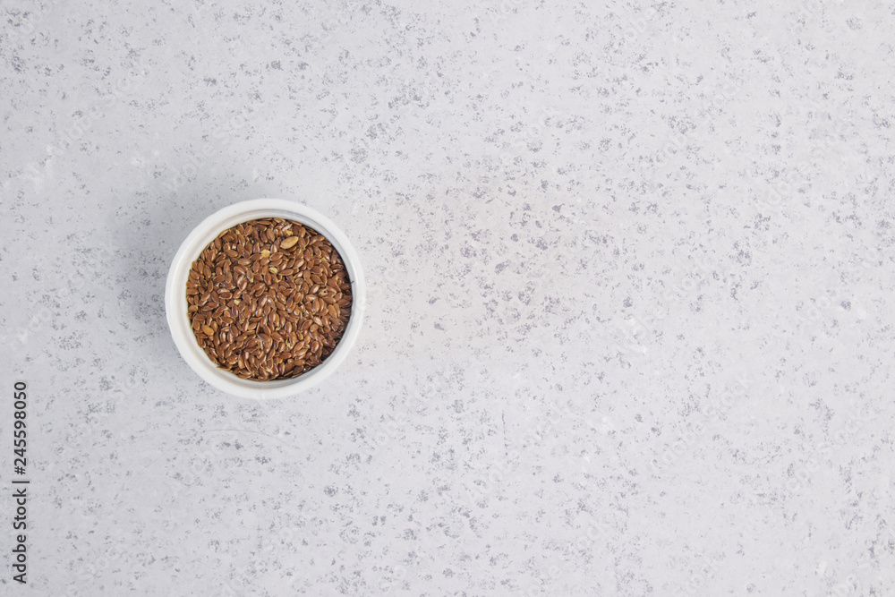 Flax seeds in white bowl on grey background, top view Flax seeds in white bowl on grey background, top view