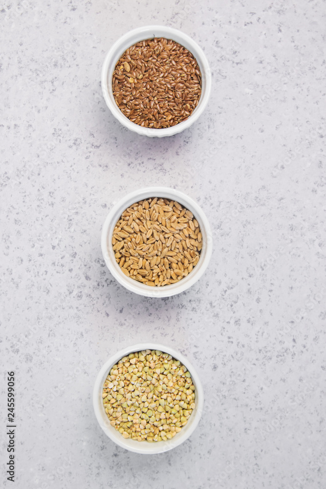 Collection of different groats on grey background. Top view of buckwheat, chia, flax, amaranth, lentils, couscous, wheat Collection of different groats on grey background. Top view of buckwheat, chia, flax, amaranth, lentils, couscous, wheat