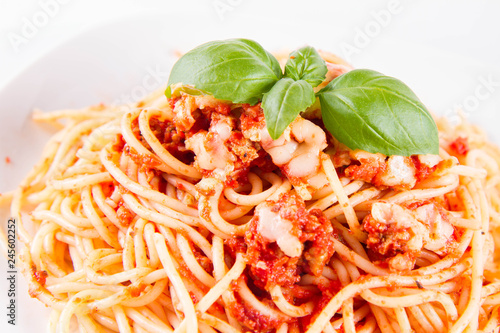 Spaghetti bolognese with melted parmesan cheese decorated with basil on a white background