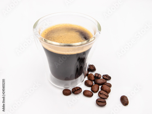 Glas of arabica espresso coffee with a few roasted coffee beans isolated on a white background
