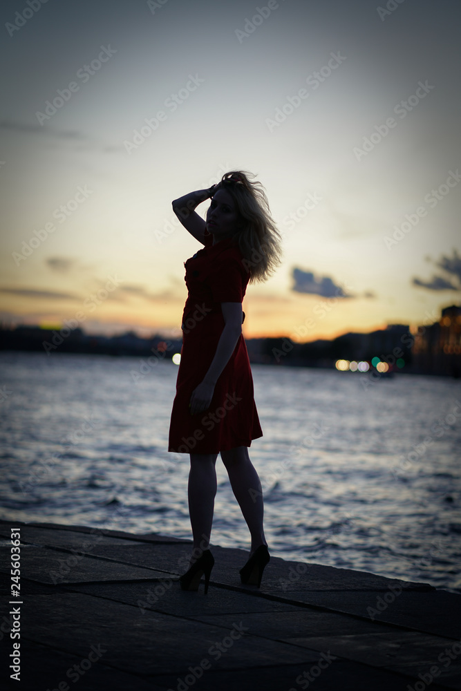 nice caucasian girl walks late at night at sunset near the river alone