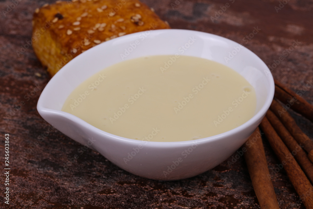 Condenced milk in the bowl with sinnamon and pastry Condenced milk in the bowl with sinnamon and pastry