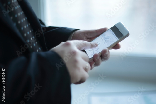 close up. a businessman uses a smartphone while standing near a work table in the office