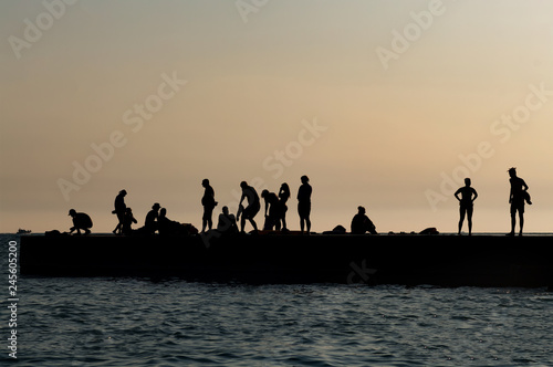 Silhouette photo of people resting on the pier after sunset. 