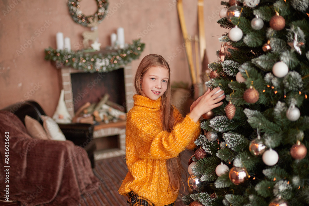 smiling teen girl decorating Christmas tree in her living room