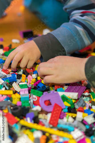 Close up of colorful plastic bricks on the floor. Early learning. Children's plastic constructor on the floor. Children's hands play a little constructor. vertical photo.