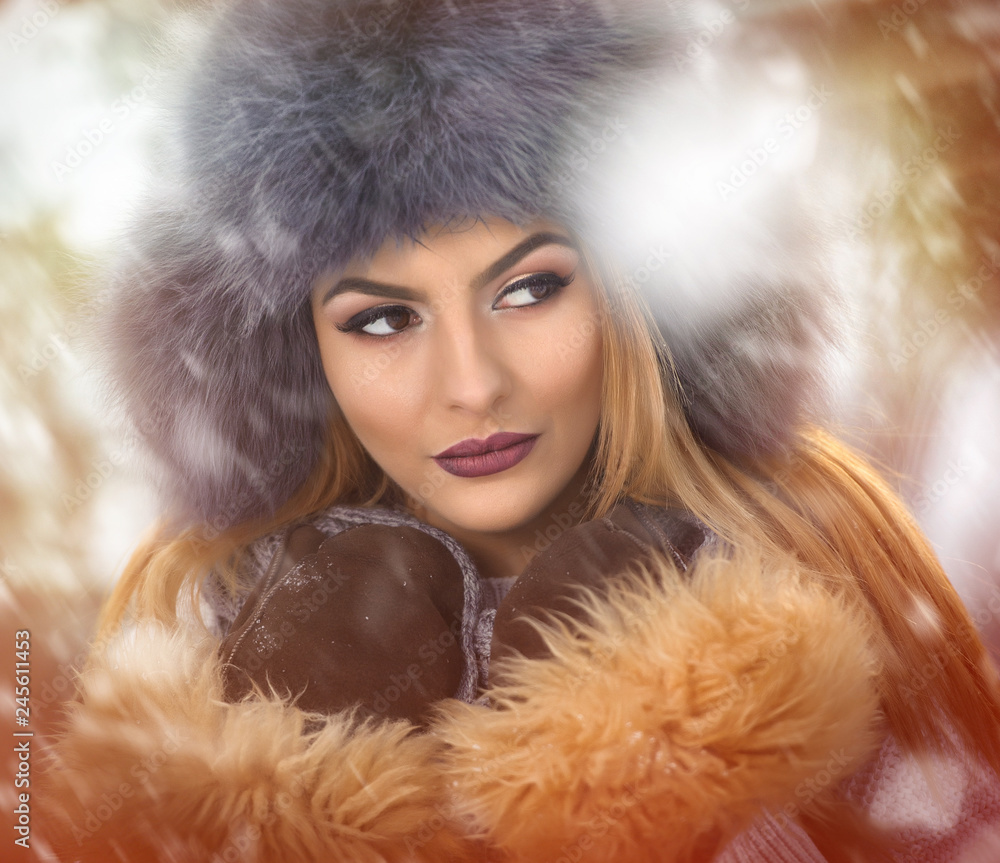 Attractive woman with brown fur cap and jacket enjoying the winter. Side view of fashionable blonde girl posing against snow covered bridge. Beautiful young female with cold weather outfit Attractive woman with brown fur cap and jacket enjoying the winter. Side view of fashionable blonde girl posing against snow covered bridge. Beautiful young female with cold weather outfit