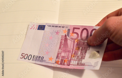 Man's hand holding a big money bill, 500 euros in one hand. The bill of 500 euros out of circulation