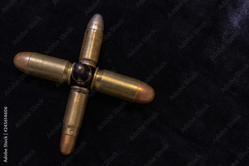 Pistol bullets gathered together in the shape of a cross. War concept. Dark background shot.