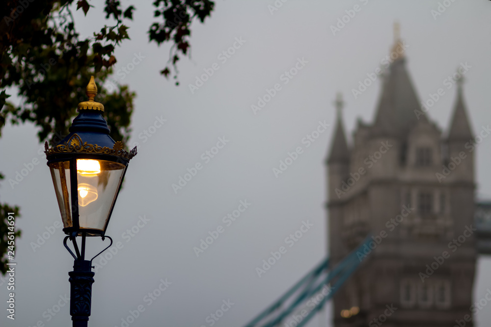 Street lantern against the Tower bridge in deep morning fog. London, the UK