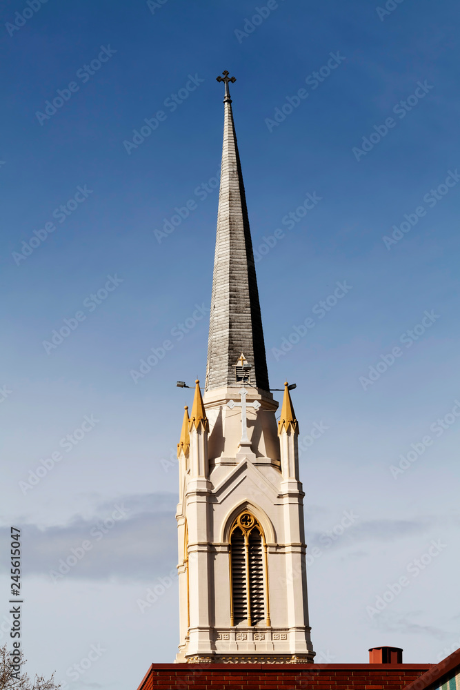 Christian Church Steeple With Cross Against Blue Sky