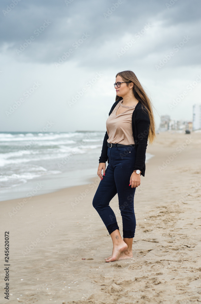 young girl with glasses posing on the beach on a cloudy day young girl with glasses posing on the beach on a cloudy day