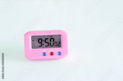Pink electronic clock on a white background. Close-up.