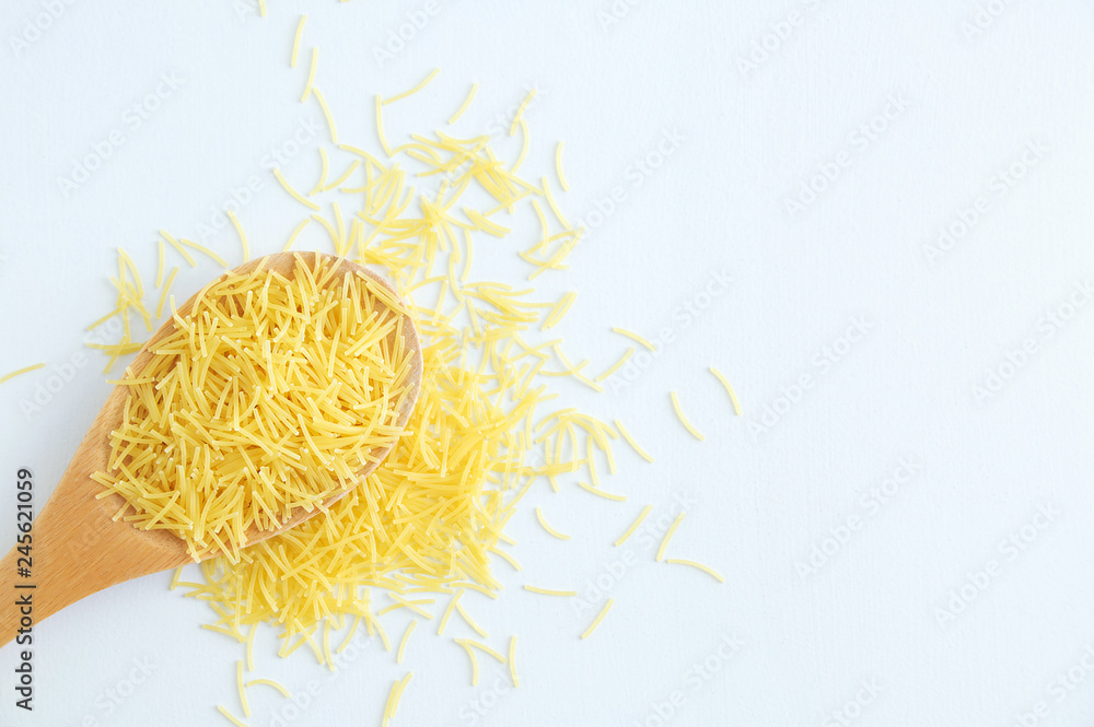 Small noodles on a wooden spoon and scattering. White background. Small noodles on a wooden spoon and scattering. White background.