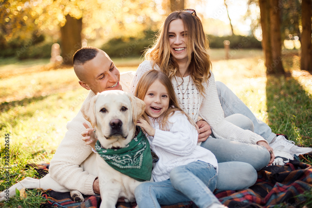 Happy beautiful family with dog labrador is having fun are sitting on green grass in park. Happy beautiful family with dog labrador is having fun are sitting on green grass in park.
