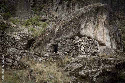 sheepfold with a stone wall under a boulder to keep in livestock next to Manteigas town, Guarda district, Portugal photo