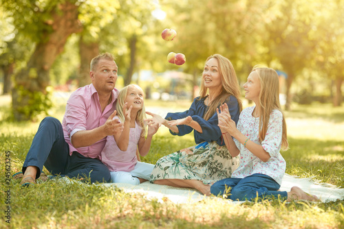 Happy man and woman with smiles playing with children on the street and picnic