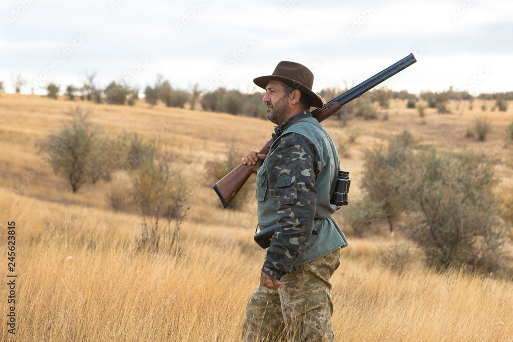 Hunter with a hat and a gun in search of prey in the steppe	