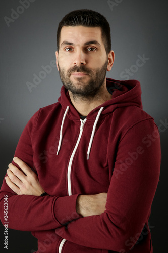 Portrait of handsome bearded man in a red hoodie against the black background