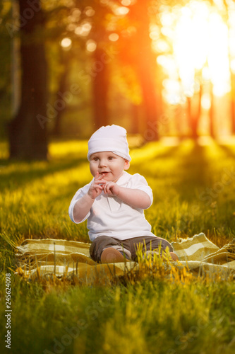 Baby in the park in the rays of sunset. Toddler on the nature outdoors. Backlight. Summertime family  scene