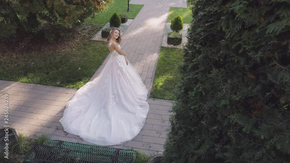 Beautiful and lovely bride in the park. Pretty and well-groomed woman. Blonde. Wedding day. Slow motion