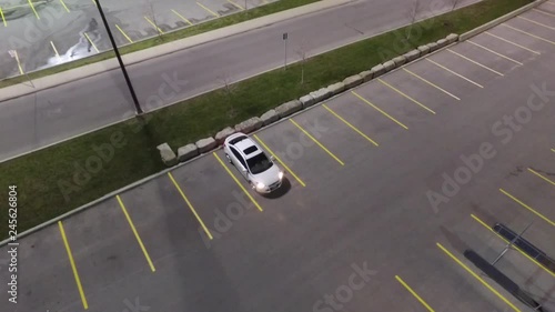 Single White Car With Sunroof And Headlamps On At Night In Empty Parking Lot Aerial View 002 photo