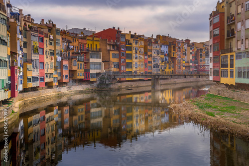 Colorful yellow  red  green houses alongside the Onyar river with reflection on the water in Girona Catalonia region Spain