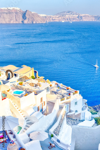 European Destinations. Amazing View of Classic White Houses and Blue Colors of Oia Village Houses And Architecture on Santorini Island in Greece. Sailing Boat in Background.
