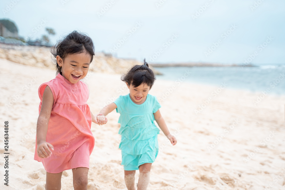two little girl smile when playing together at the beach two little girl smile when playing together at the beach