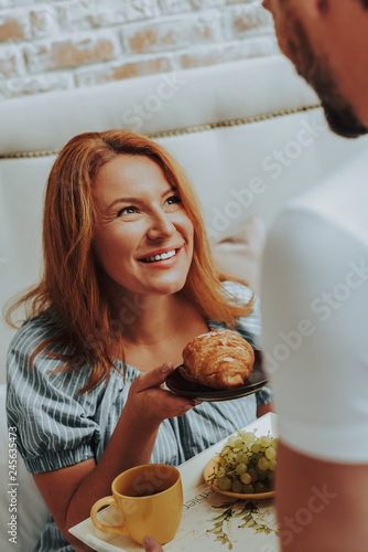 Happy smiling woman holding croissant on plate