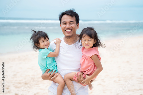 portrait a father carries his two daughter smile look at camera