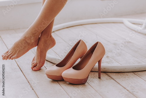 Businesswoman taking off high heels shoes after work at home photo