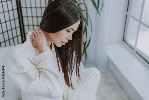 Disappointed asian woman expressing pain near window photo