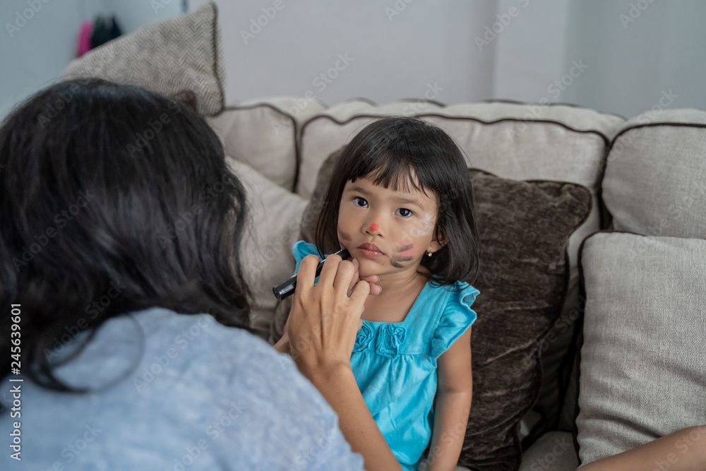 asian mother face painting her little daughter asian mother face painting her little daughter