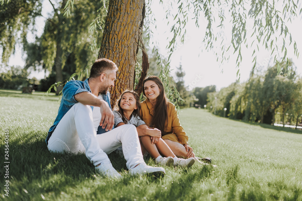 Smiling family is having rest on grass Smiling family is having rest on grass