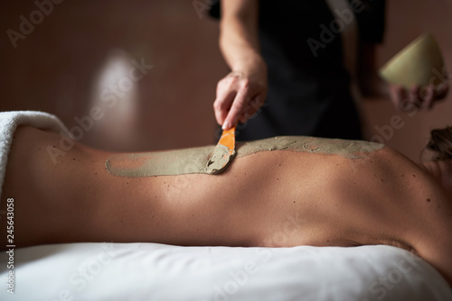 Young lady with spreading spa mud on back