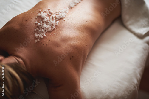 Young lady lay on massage table with mineral salt