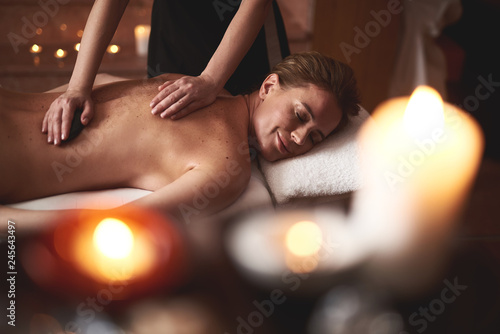 Young lady have relaxing massage with warm stones