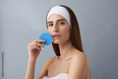 Slika na platnu Beautiful young lady in white headband holding blue sponge