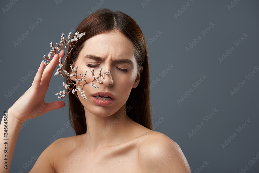 © Yakobchuk Olena - Attractive brunette girl holding beautiful sprigs with white flowers near cheek