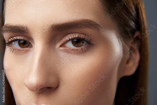 Charming young woman with beautiful brown eyes staring at you