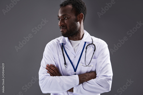 Confident professional afro american doctor standing against gray background