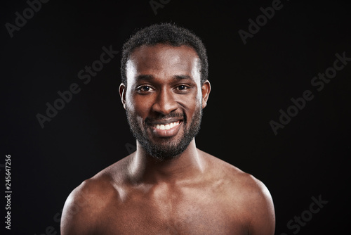 Cheerful afro American man standing against black background