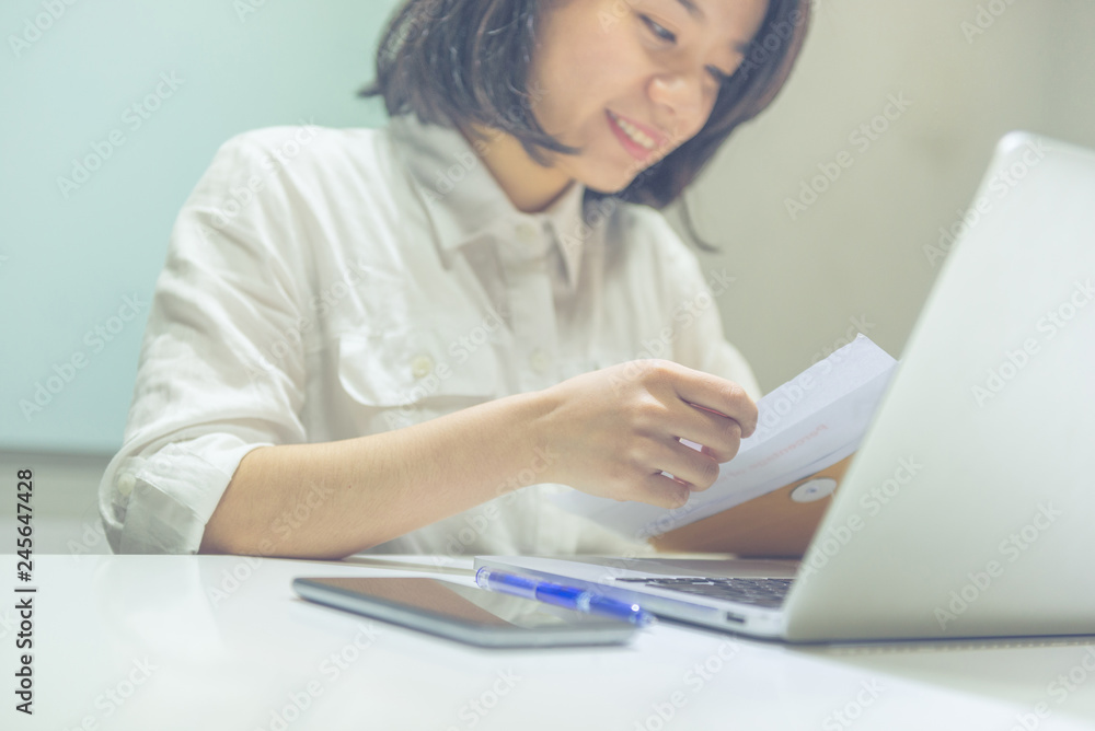 Young Asian businesswoman reading letter from brown envelope Young Asian businesswoman reading letter from brown envelope