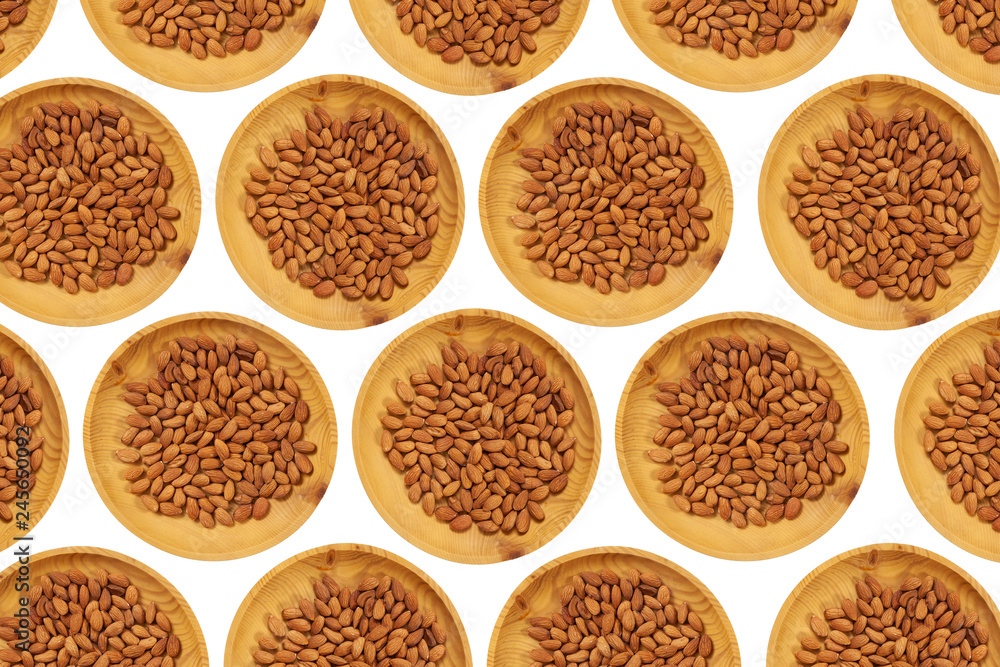 Peeled almonds in a wooden pine plate on a white isolated background. Row of bowls with almonds nuts, top view. Peeled almonds pattern Peeled almonds in a wooden pine plate on a white isolated background. Row of bowls with almonds nuts, top view. Peeled almonds pattern
