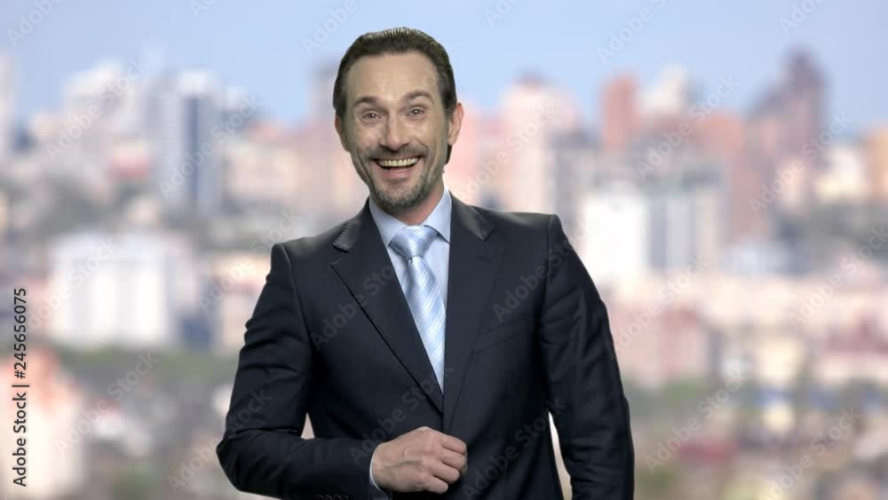Portrait of laughing mature businessman. Bearded male executive is laughing and looking at camera. Blur city background. Portrait of laughing mature businessman. Bearded male executive is laughing and looking at camera. Blur city background.