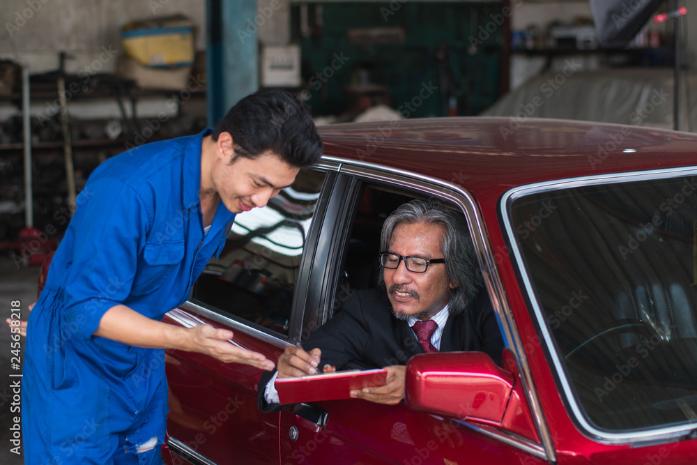 auto service, repair, maintenance concept mechanic with clipboard and car owner businessman checking repair items car
