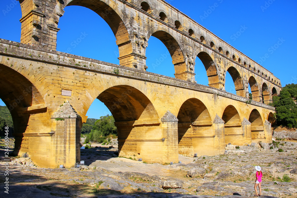 Young woman standing near Aqueduct Pont du Gard in southern France
